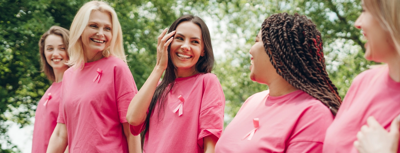 A group of women raising their hands for Breast Cancer awareness.